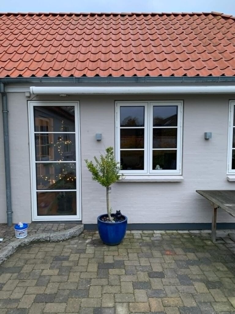 Husfacade med blå potteplante og rødt tegltag
